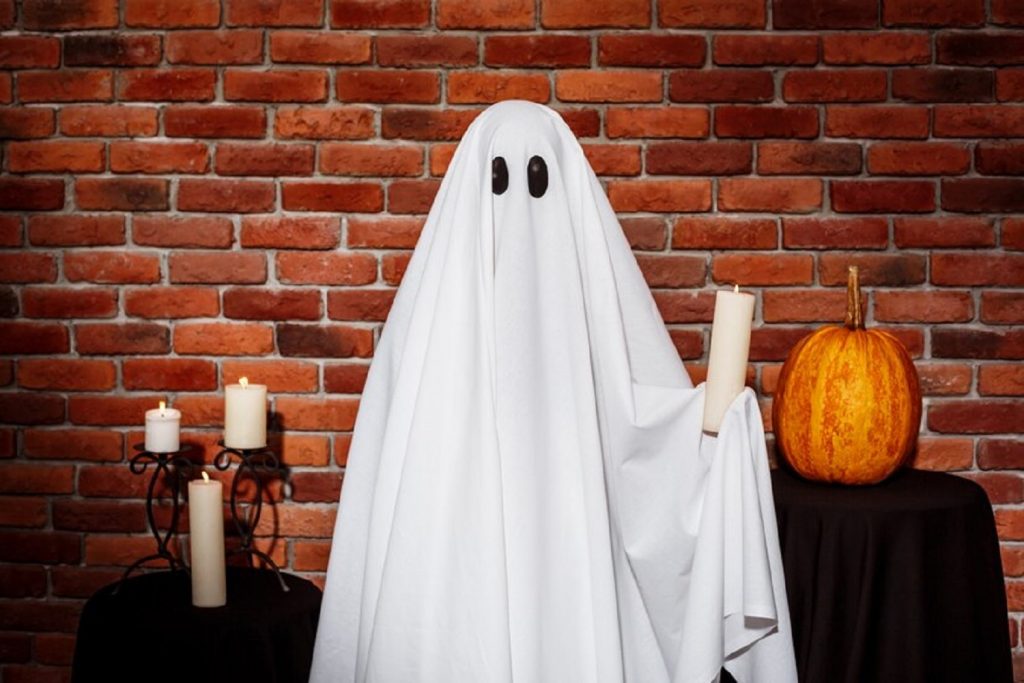 ghost-holding-candle-brick-wall-halloween-party_176420-8381